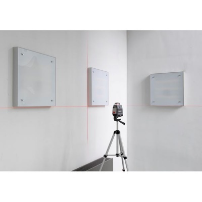 Tripé com ferramenta de medição a laser e paredes com linhas vermelhas e quadros de vidro