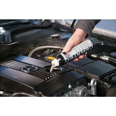 Frasco branco a despejar líquido no motor preto de um carro