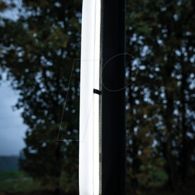 Luz LED vertical branca num poste preto ao ar livre com árvores ao fundo