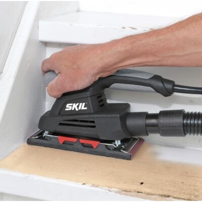 Lixadora elétrica preta SKIL a ser usada numa superfície de madeira clara
