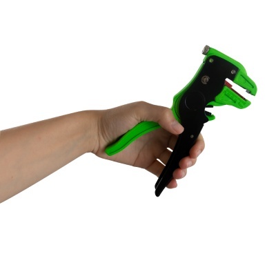 Ferramenta de corte verde e preta na mão com fundo branco