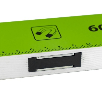 Régua verde com marcações centimétricas e símbolo de íman