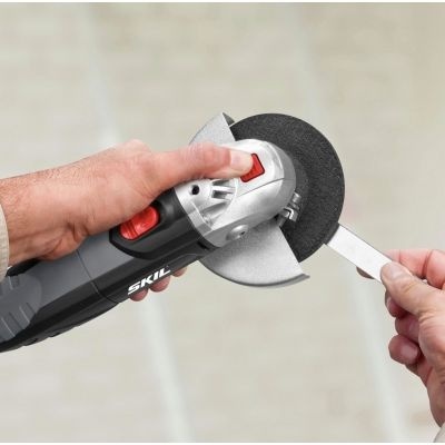 Rebarbador elétrico SKIL com disco abrasivo preto a cortar peça metálica branca