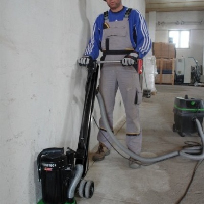 Homem a usar máquina de limpeza no chão numa garagem.