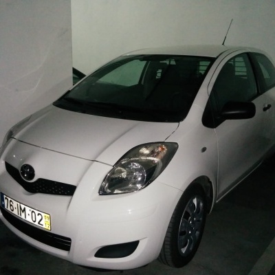 Carro branco compacto estacionado num parque de estacionamento interior