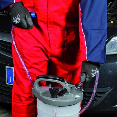 Pessoa com fato vermelho e azul usando equipamento portátil de limpeza junto a viatura preta