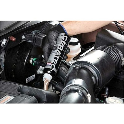 Mão com luva a verter líquido de frasco preto no motor do carro