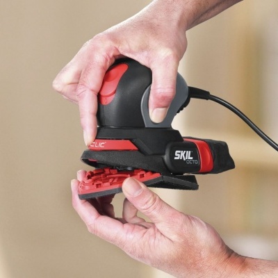 Lixadora elétrica preta e vermelha SKIL em uso
