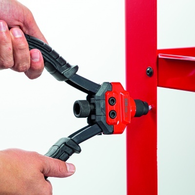 Ferramenta manual preta e vermelha a ser usada numa estrutura metálica vermelha.