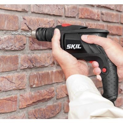 Furadeira elétrica SKIL preta a furar parede de tijolos