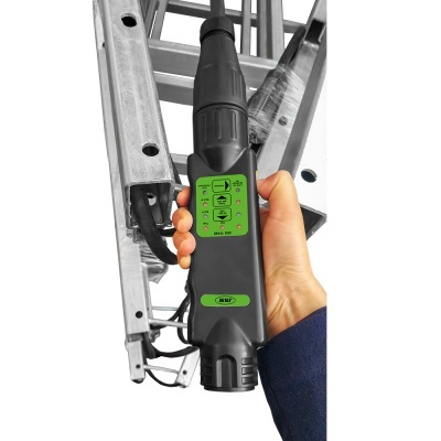 Dispositivo preto com etiqueta verde segurado junto a uma estrutura metálica prateada