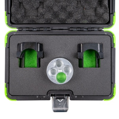 Estojo rígido verde com espuma preta e três objetos organizados num interior