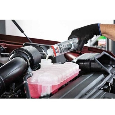 Frasco de LIQUI MOLY RADIATOR CLEAN sendo despejado em reservatório de líquido de radiador de carro