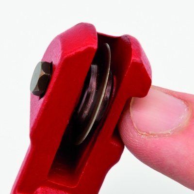 Ferramenta pequena vermelha com peça metálica e parafuso entre dedos