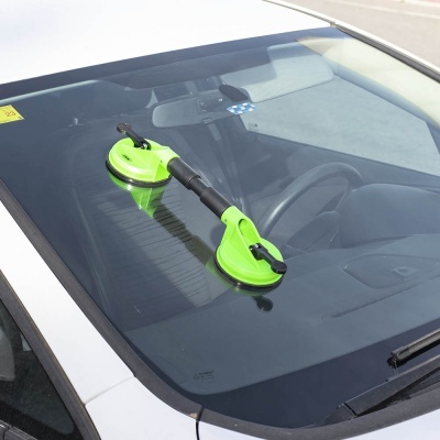 Ferramenta de sucção verde com pega preta no para-brisas de carro branco