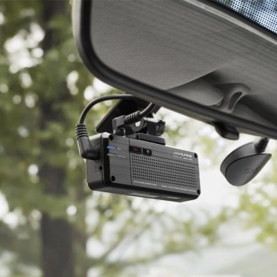 Câmara de vídeo Alpine preta instalada no para-brisas de um carro com cabos conectados