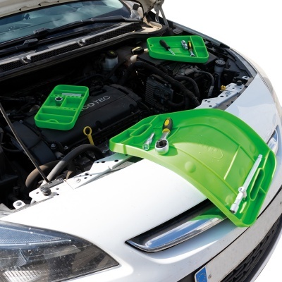 Tabuleiros verdes com ferramentas sobre capô de carro branco na manutenção do motor