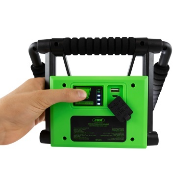 Aparelho portátil verde com alça preta e ecrã digital sendo operado por uma mão