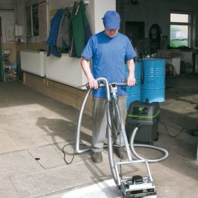 Homem a operar máquina de limpeza industrial num ambiente de oficina