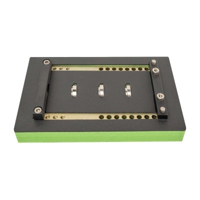 Suporte retangular preto com base verde e orifícios metálicos