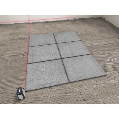 Seis placas de pavimento cinzentas sobre chão preparado com ferramenta e linha laser