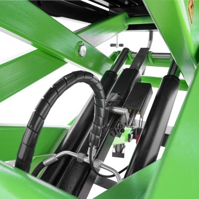 Componentes hidráulicos pretos numa estrutura metálica verde