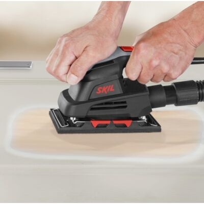 Lixadora elétrica preta e vermelha SKIL a ser usada numa superfície clara