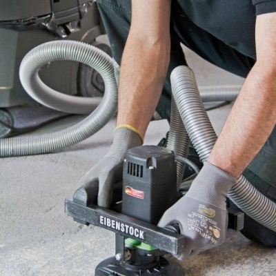 Máquina elétrica EIBENSTOCK com mangueira de sucção a ser operada por pessoa com luvas cinzentas.