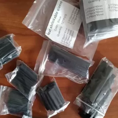 Pacotes de tubos termorretráteis pretos com etiquetas em sacos transparentes sobre madeira