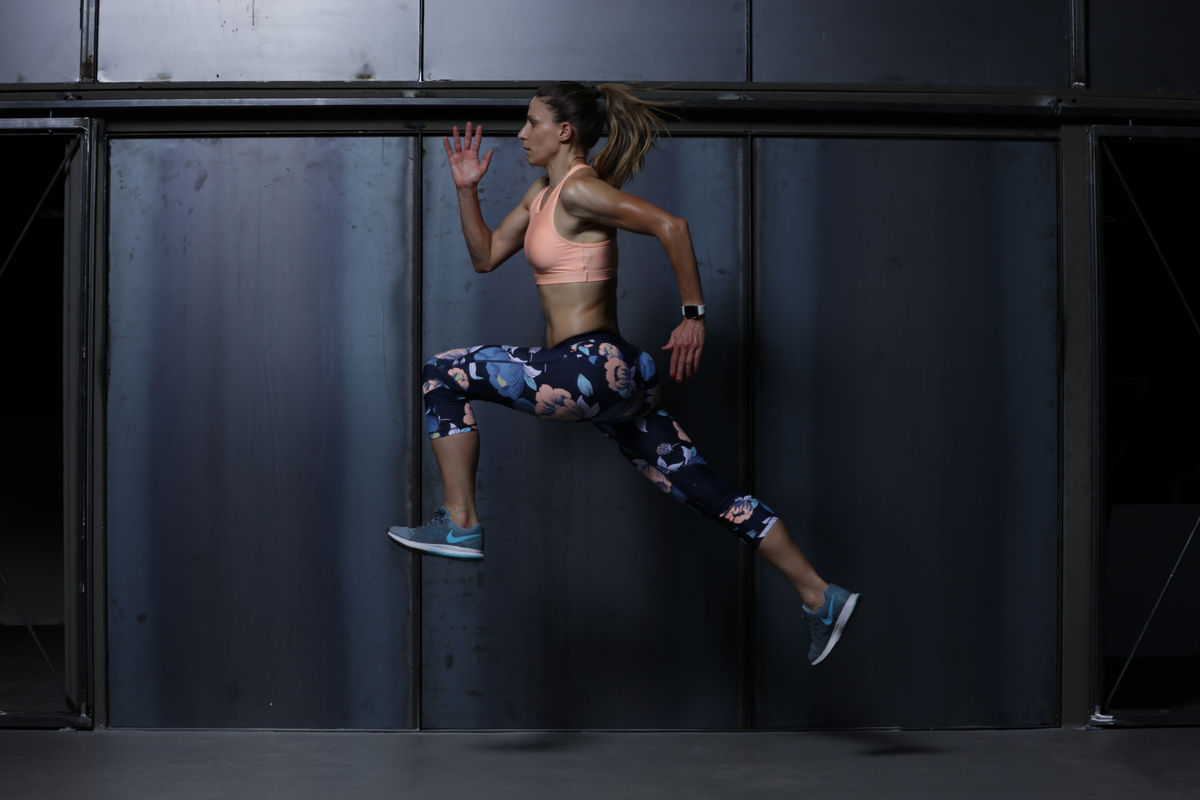 O papel da pliometria na performance desportiva Mulher a saltar em roupa de desporto com leggings florais e top cor de rosa