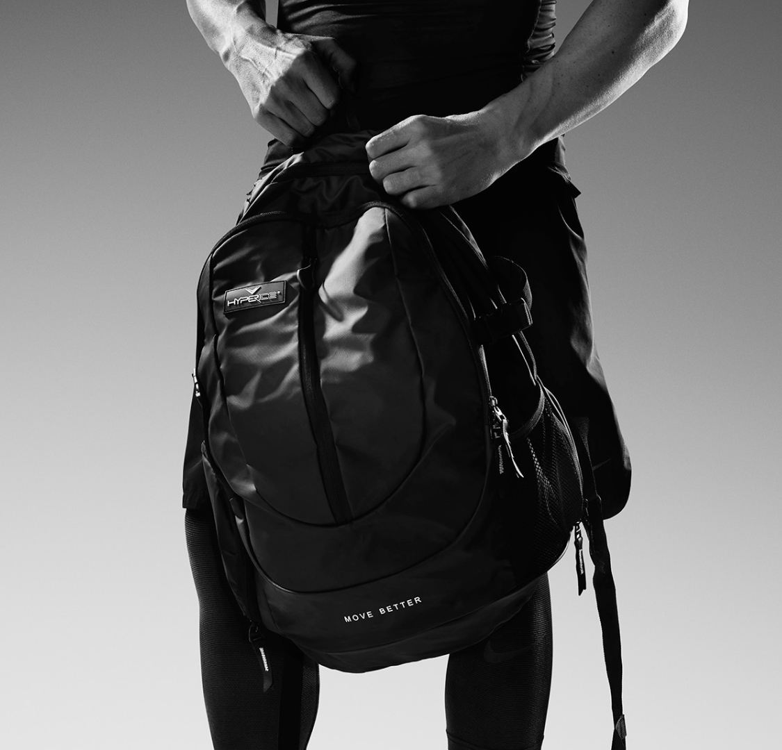 Hyperice Teck Pack Mochila preta com frase MOVE BETTER segurada por pessoa com roupa preta