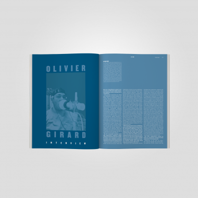 Revista aberta a uma entrevista com fotografia e texto sobre fundo azul