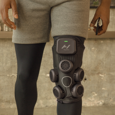 Joelheira preta com ventiladores numa perna humana