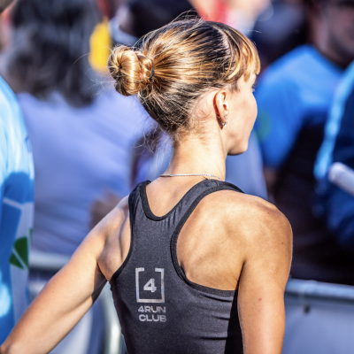 Pessoa de costas com top desportivo preto 4RUN CLUB num ambiente exterior