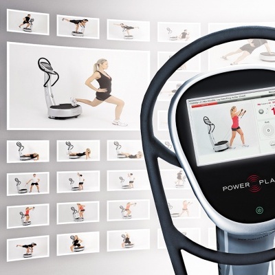 Equipamento de exercício Power Plate com ecrã tátil e imagens a mostrar exercícios na parede