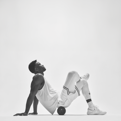 Homem em roupa desportiva branca usando rolo de massagem preto