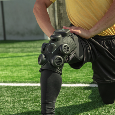 Proteção preta com ventilas no joelho num campo de relva artificial