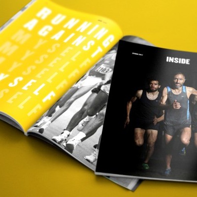 Revistas abertas com temas de corrida, uma página amarela com texto branco e outra página preta com três corredores