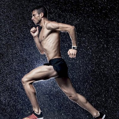 Homem a correr sob chuva com calções pretos e sapatilhas vermelhas e pretas