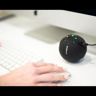 Câmara de videovigilância preta esférica numa secretária branca junto a teclado e rato