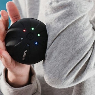 Dispositivo eletrónico preto redondo com luzes LED e marca ARKTEC na mão de uma pessoa com casaco cinza