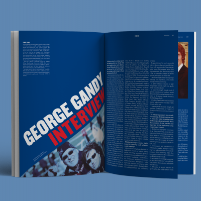 Livro aberto com página azul e texto 'GEORGE GANDY INTERVIEW' e outra página com texto e imagem de pessoa.
