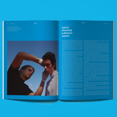 Revista aberta com texto azul e fotografia de dois homens, um cortando cabelo do outro