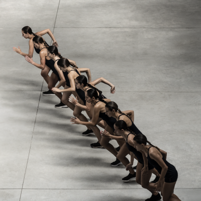 Mulheres em posição de corrida vestidas de roupa desportiva preta num piso de cimento cinza.