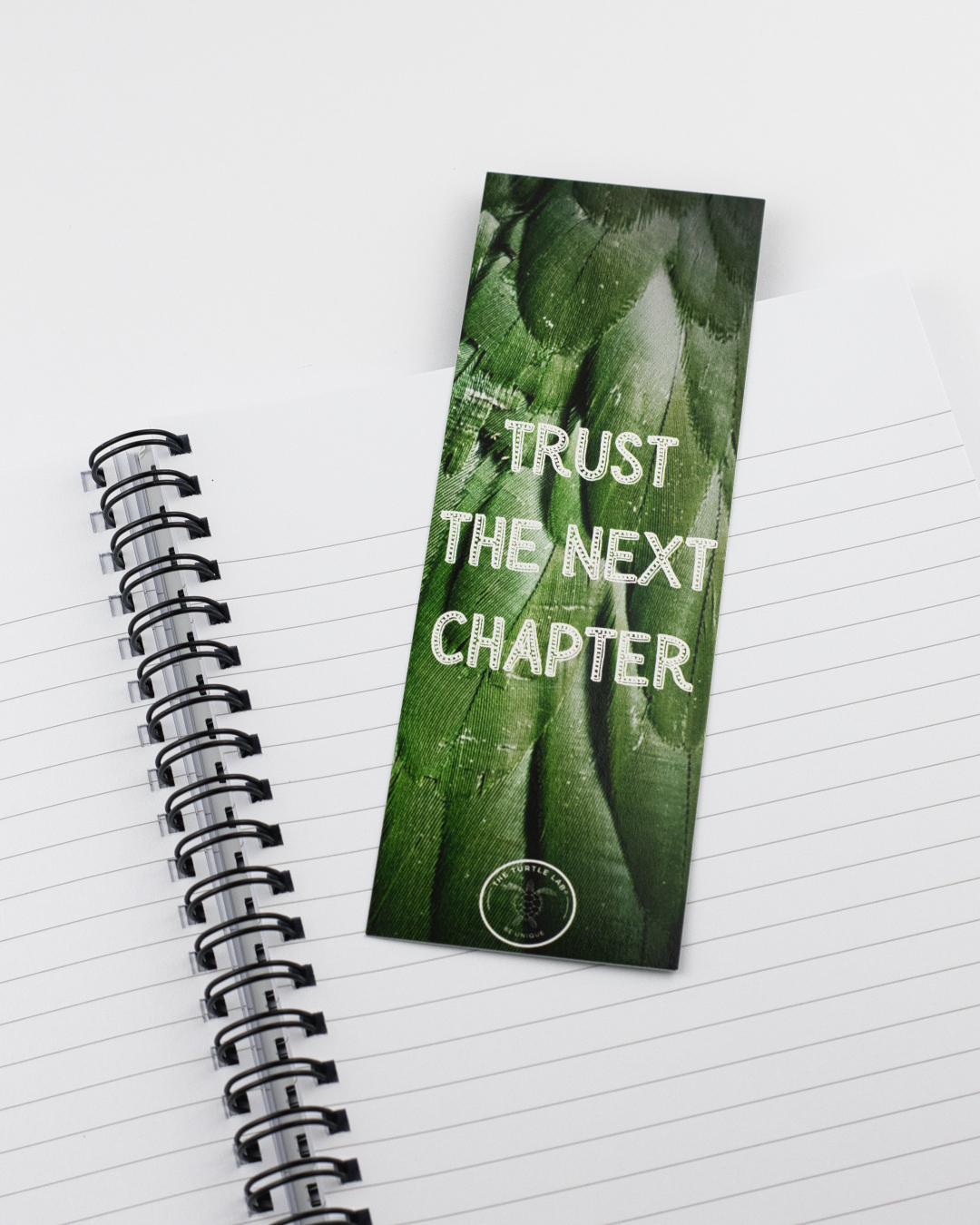 Marcador de livro verde com texto branco sobre caderno pautado espiral