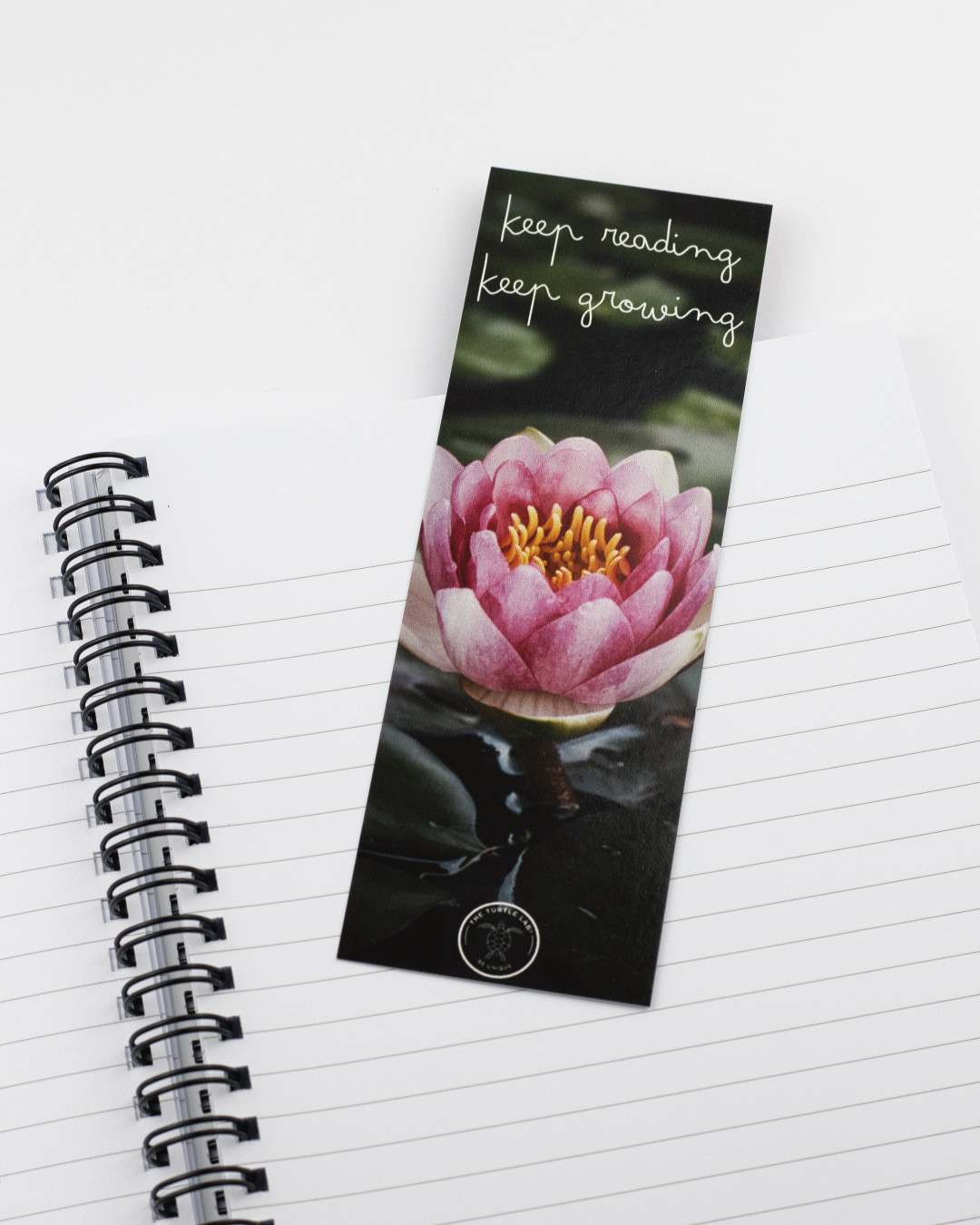 Marcador de páginas com flor de lótus rosa e caderno espiral aberto