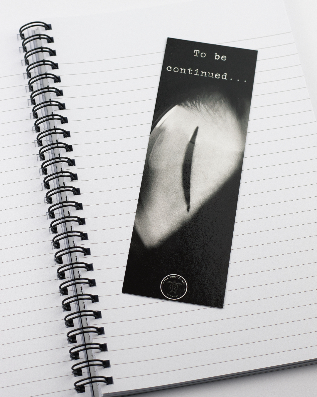 Marcador de páginas preto com imagem de um olho e texto 