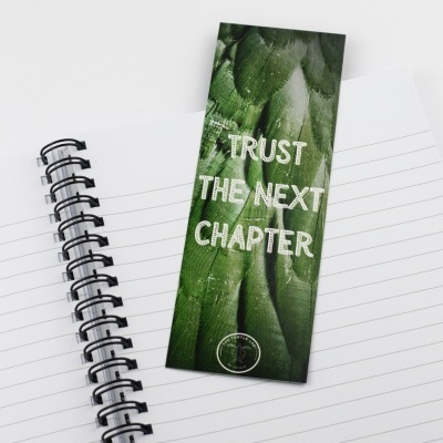 Marcador de livro verde com texto branco sobre caderno pautado espiral