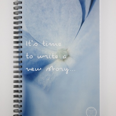 Caderno espiral azul com texto e selo branco na capa