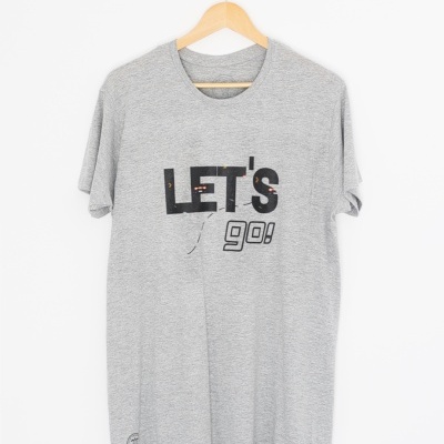 T-shirt cinzenta com texto estampado LET'S go! pendurada numa cabide de madeira